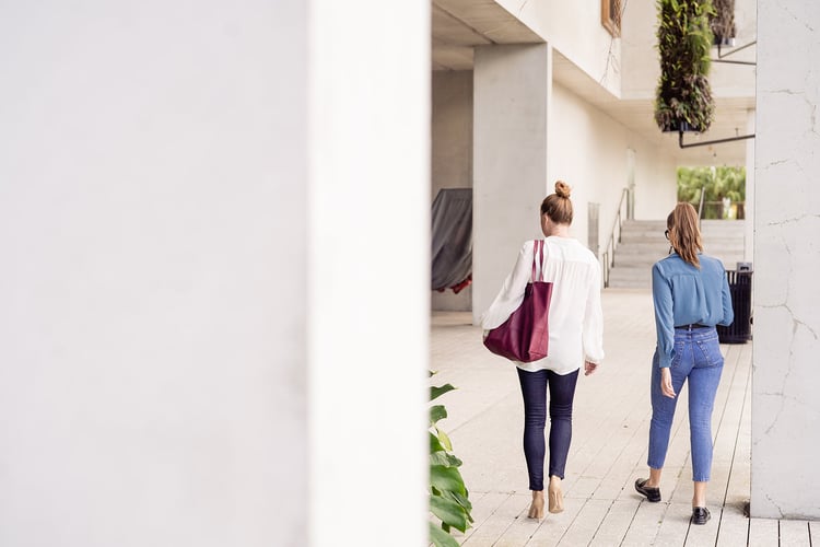 two women walking away through a hallway