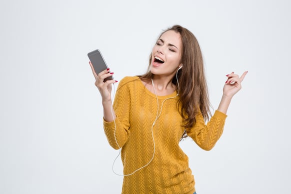 Portrait of a happy woman listening music in headphones isolated on a white background