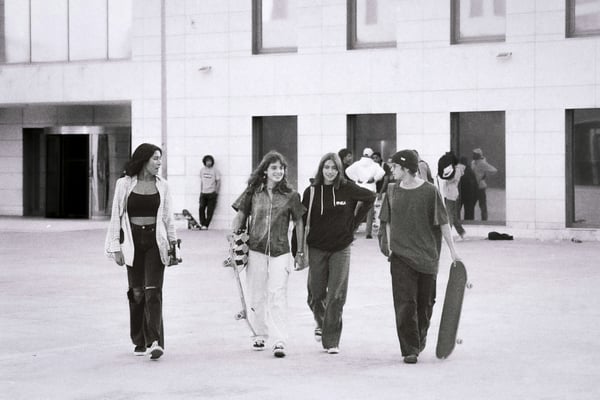 A group of young people walking with a building behind them. Campus media for generation alpha.