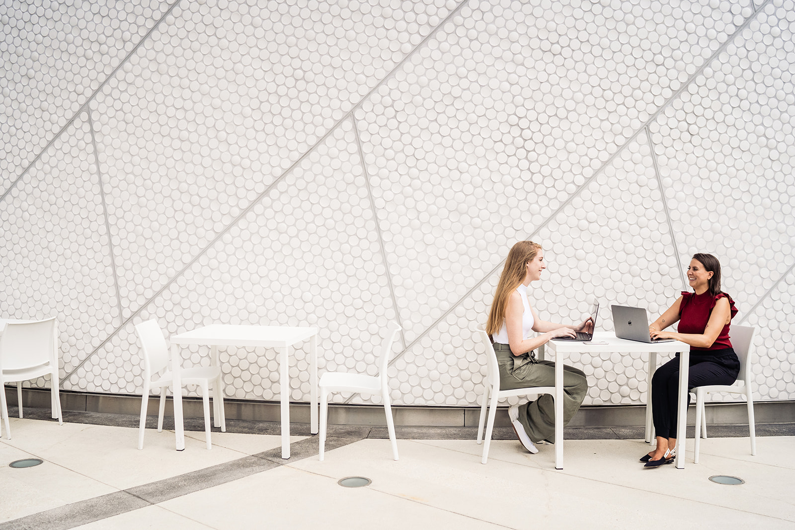 Campus OOH Specialists - two women sit facing one another at a small table with their laptops