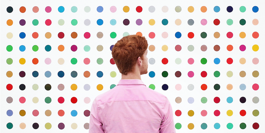 Man in pink shirt against a colorful poka dot wall